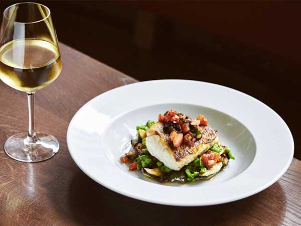 Plato de comida con vino representando la calidad y control en procesos de automatización industrial en el sector de alimentación y bebidas