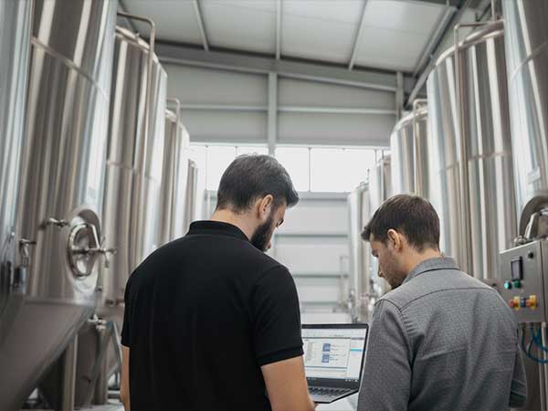 Técnicos supervisando tanques de producción con software de automatización industrial